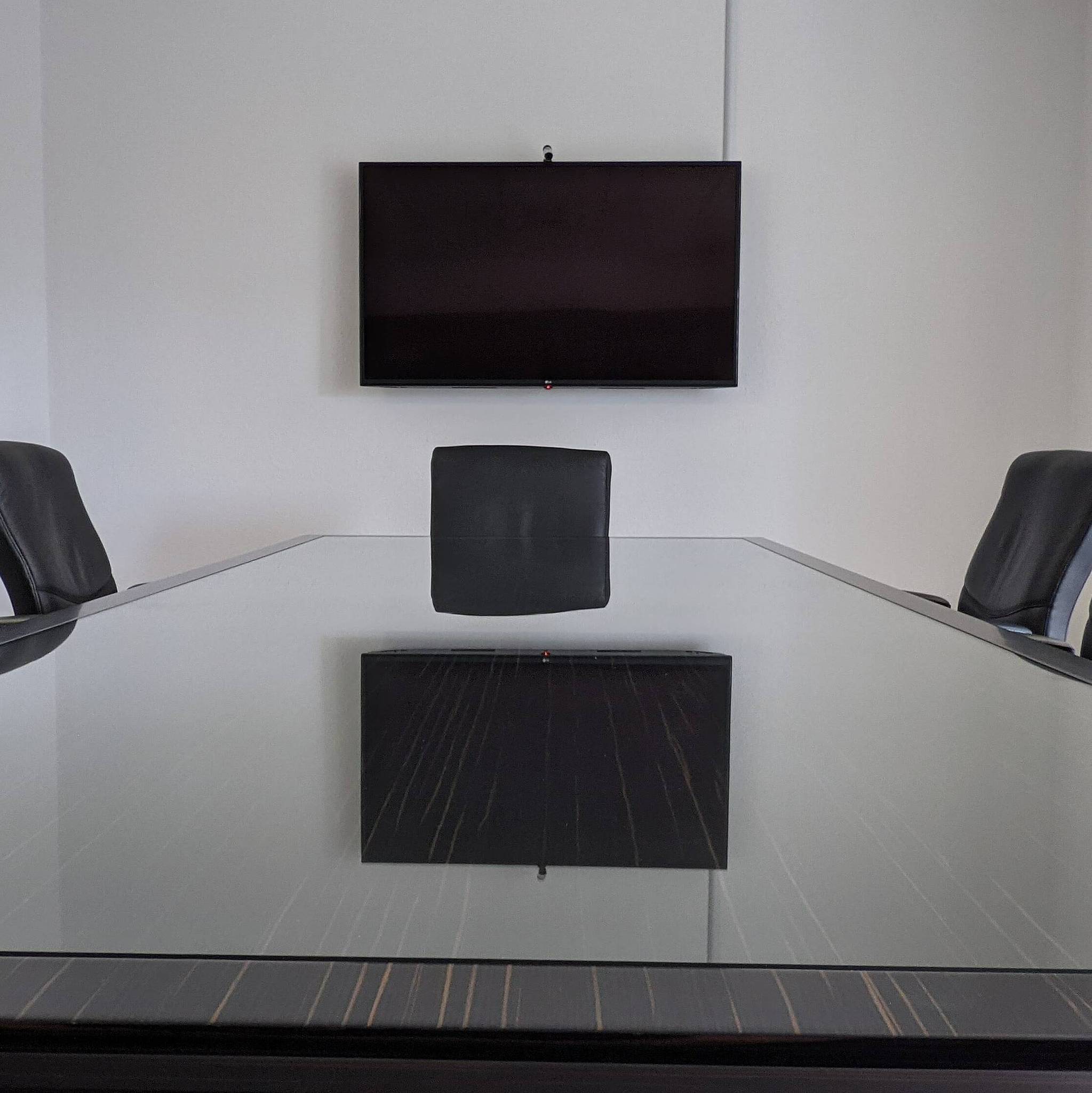 Zimmer mit Tisch und Stühlen, Monitor an der Wand